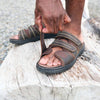 Close-up of man wearing the Propet Hatcher sandal footwear outside and adjusting the hook-and-loop straps while standing.