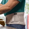 Close-up of a person wearing ActiMove high-density foam back support belt in gray. The belt features adjustable straps and a robust design, ideal for ergonomic back support and back pain relief.