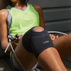 Lifestyle image of woman wearing Actimove Sport Knee Support Open Patella while holding jump-rope and sitting outside. Confidently work out, run or cycle, as this sleeve doesn't overly restrict movement.
