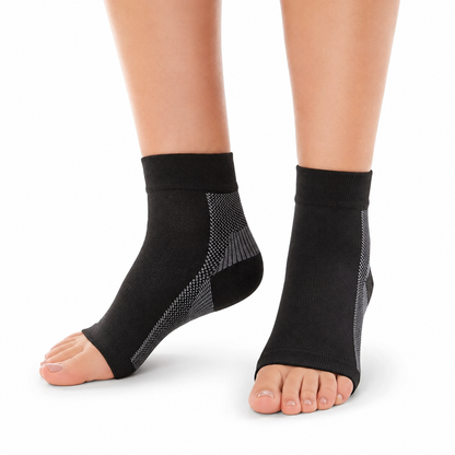 Black ankle support sleeves worn on a person's feet, shown against a plain white background.