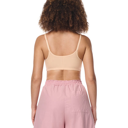 A woman shown from the back wearing a light beige wireless sports bra and dusty pink pants against a plain white background.
