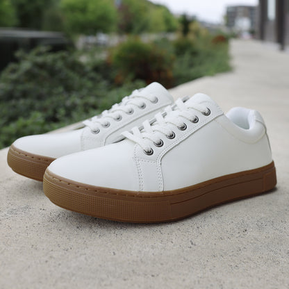 Propet Koda Men's Platform Sneaker White sneakers with brown soles on a concrete surface with greenery in the background
