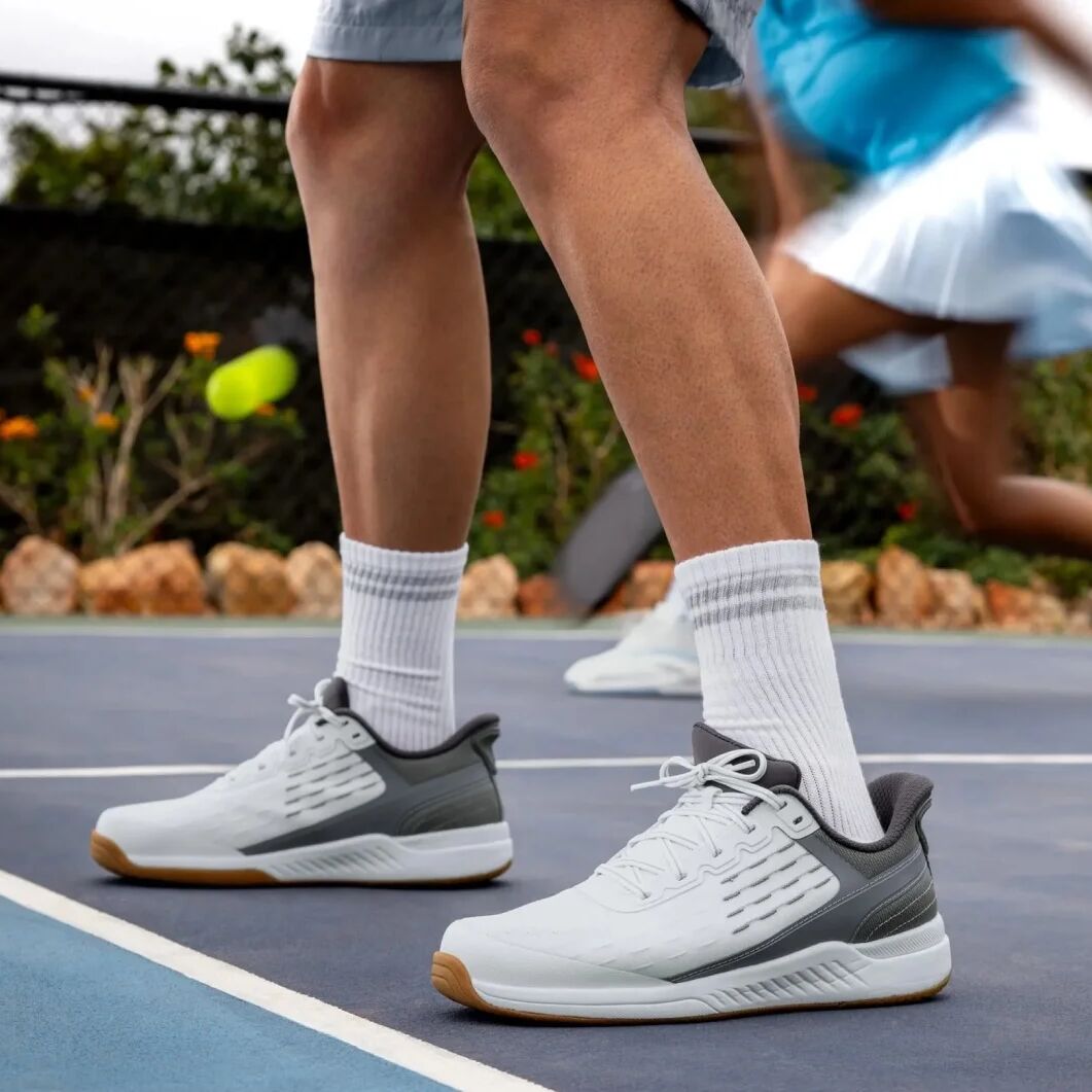 Tennis player on a court wearing white and gray sneakers with socks.