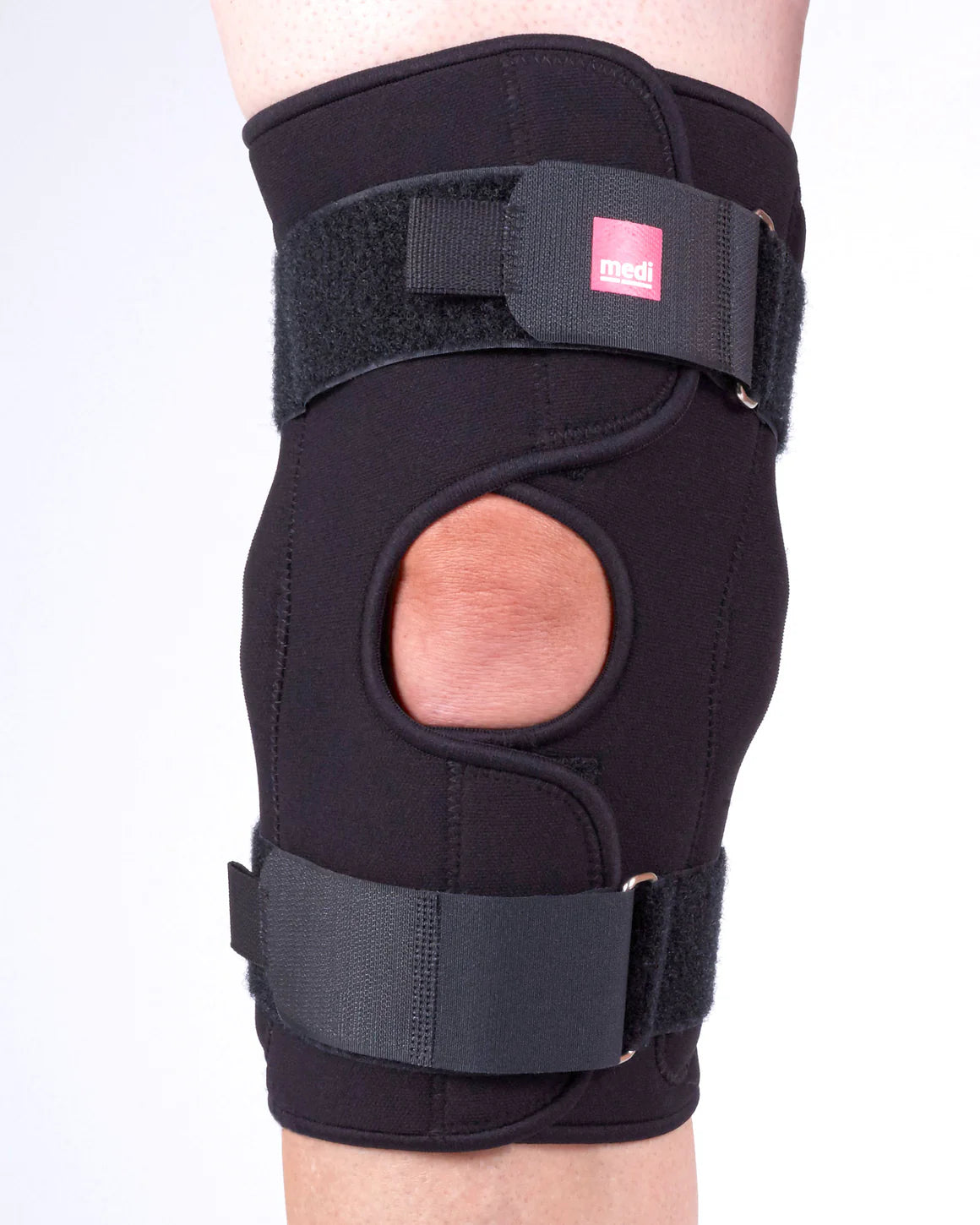 Black knee brace on a person's leg with a white background