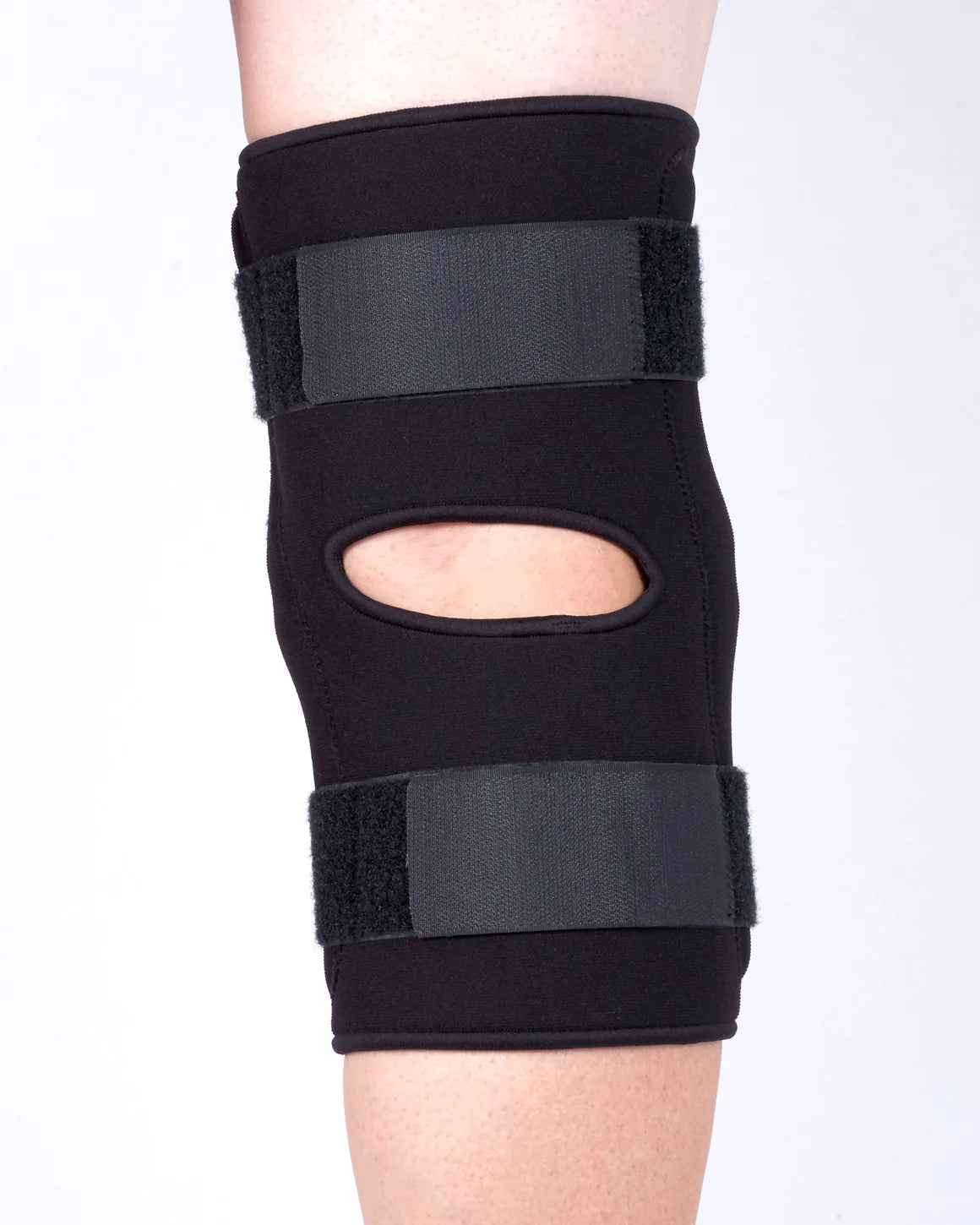 Black knee brace on a person's leg against a white background