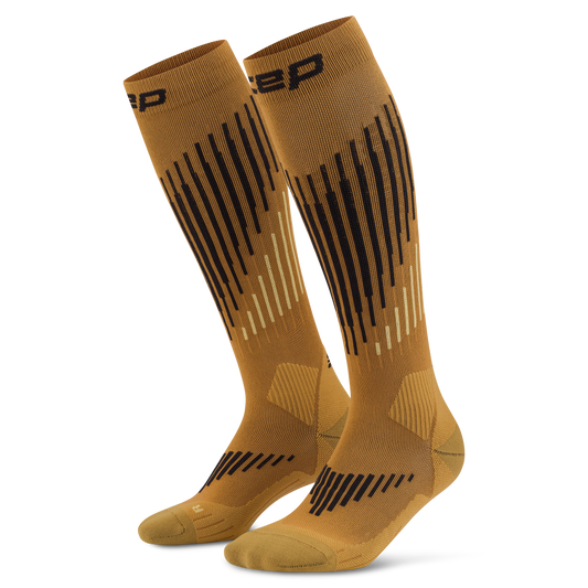 CEP Men's Ski Touring Merino Tall Socks - A pair of knee-high athletic socks in a warm camel brown color, featuring black and light beige geometric stripe patterns and the brand logo 'CEP' near the top cuff, set against a plain white background.