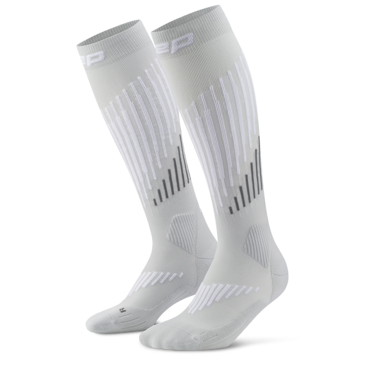 CEP Men's Ski Touring Merino Tall Socks - A pair of light gray athletic knee-high socks with white and dark gray geometric stripe patterns on the legs, displayed against a solid white background.